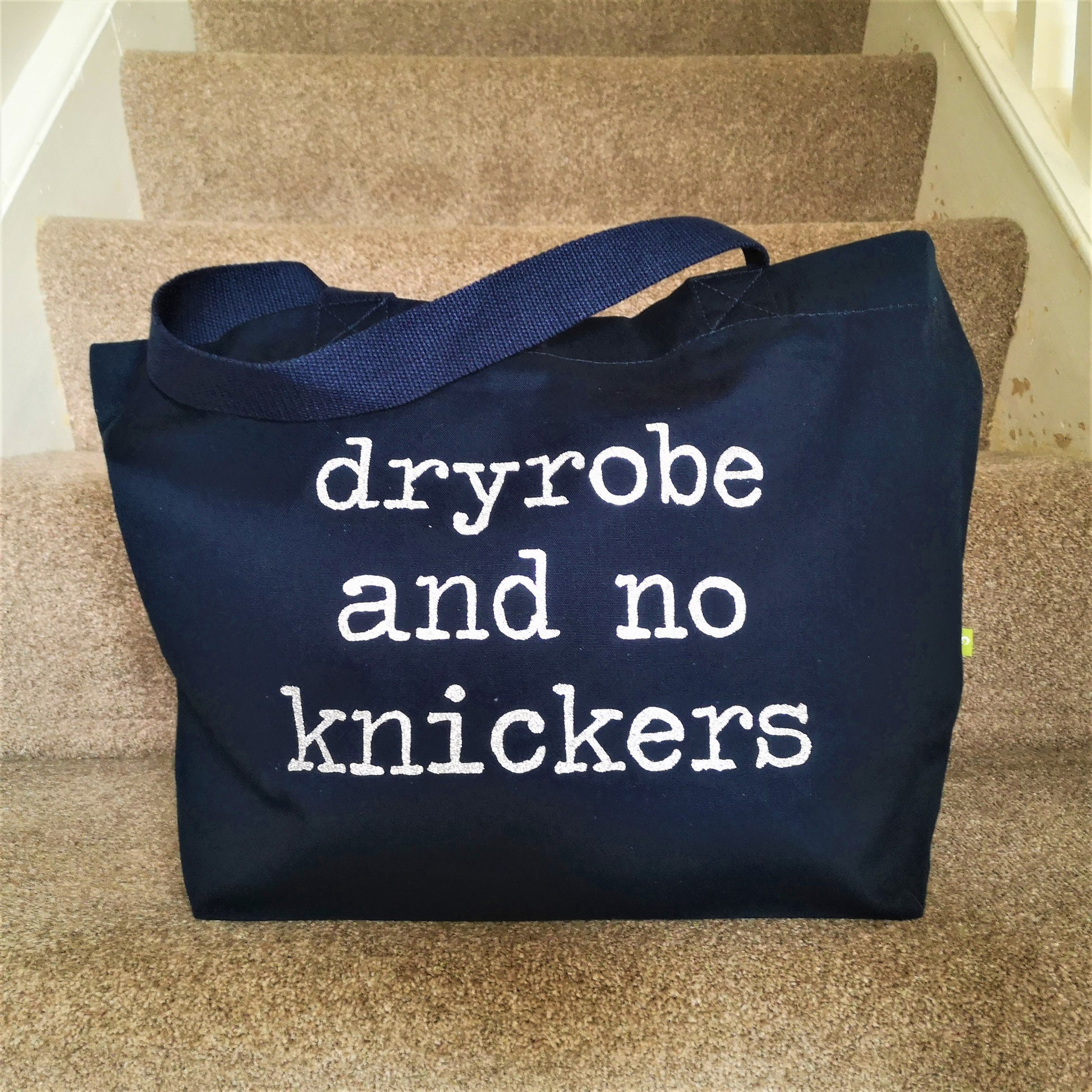 A navy organic cotton tote with toggle closing, with the following slogan written in type font on the front - Dryobe and no knickers