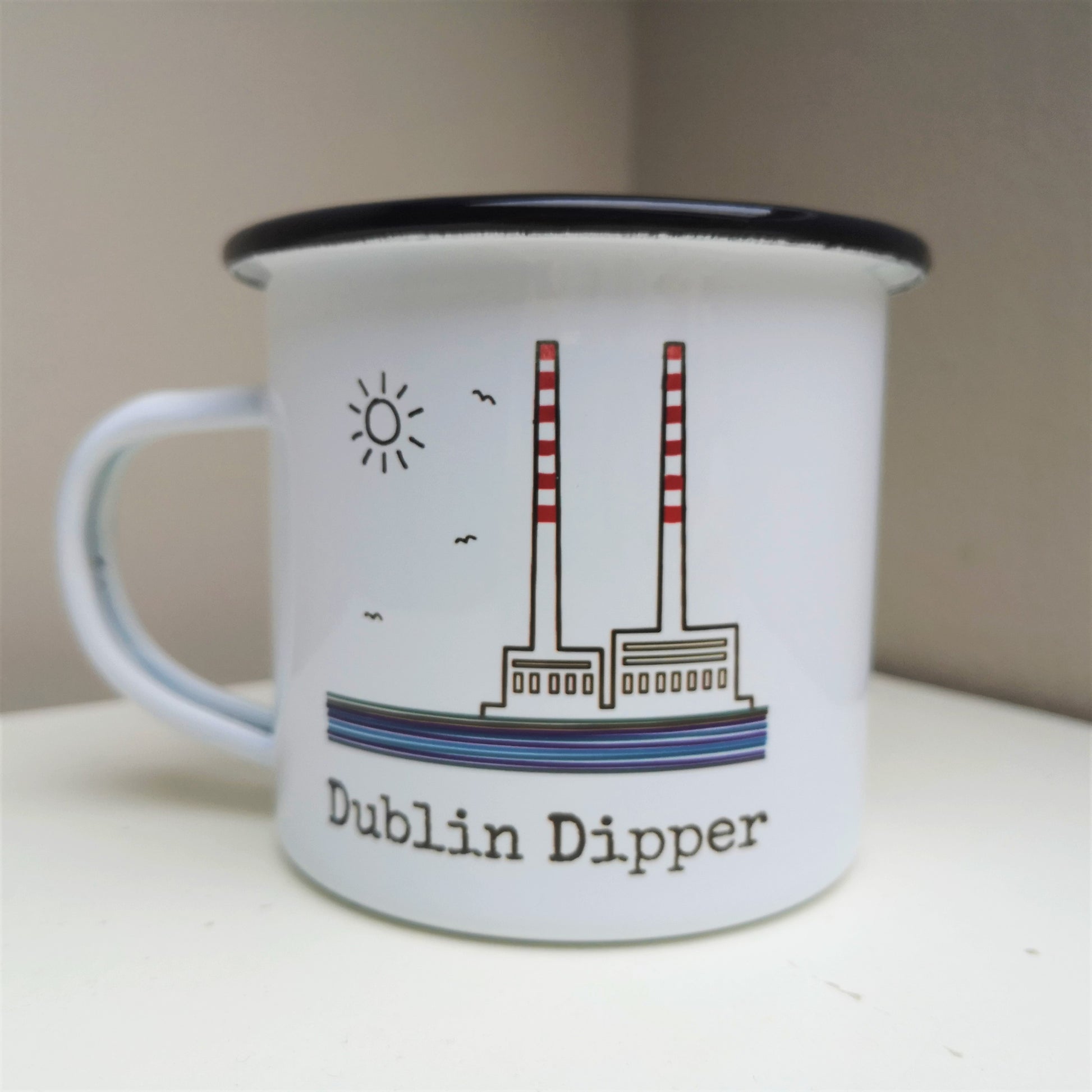 A white steel enamel mug with the poolbeg towers on it, with DUBLIN DIPPER written in type font below
