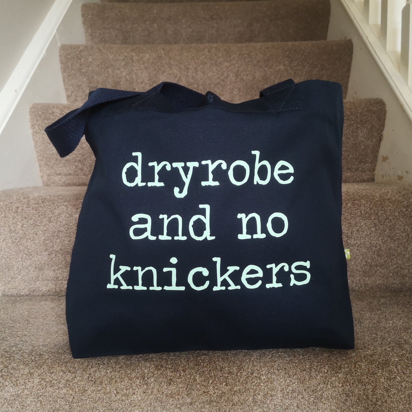A navy organic cotton tote with toggle closing, with the following slogan written in type font on the front - Dryobe and no knickers
