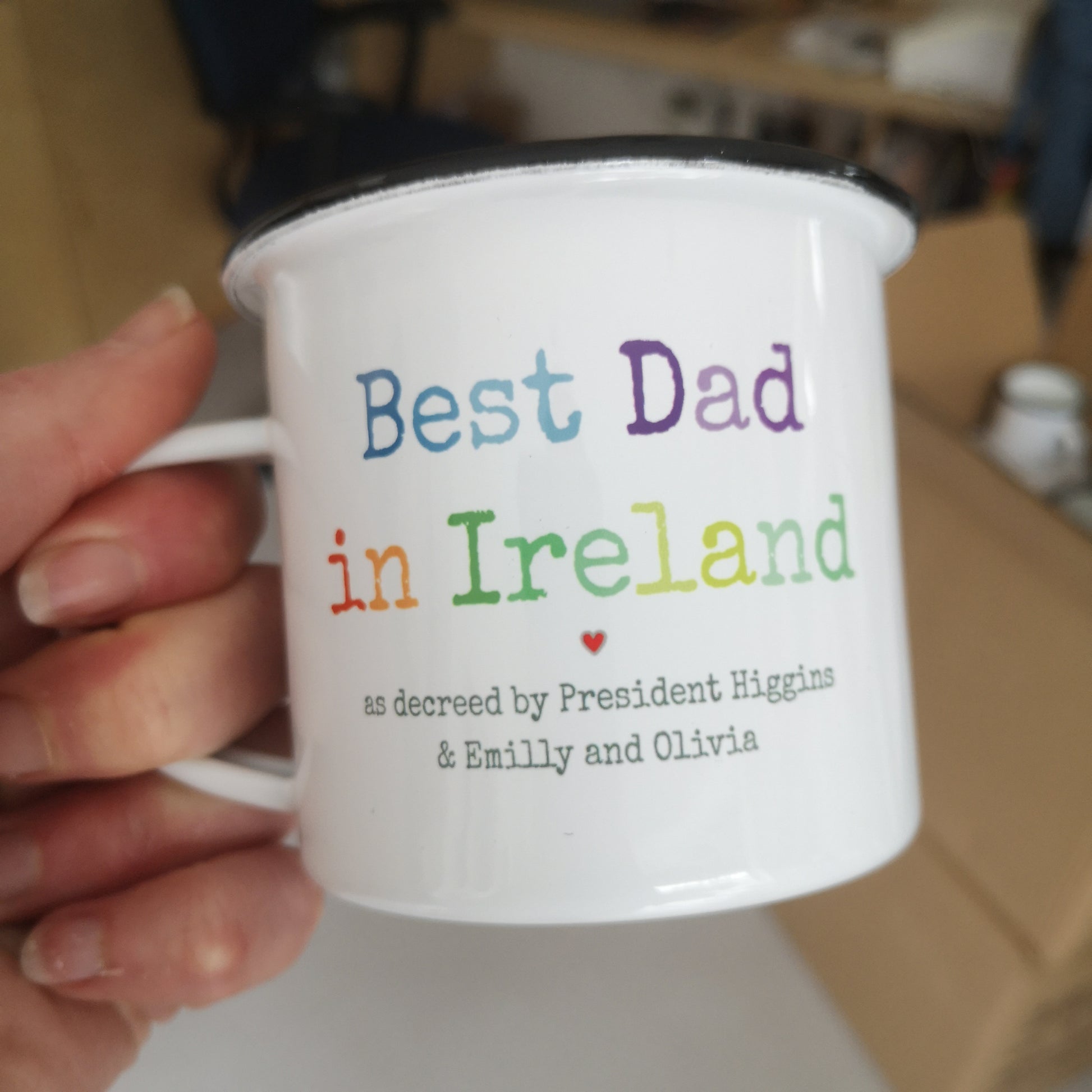 A White enamel mug with a black rim with the following on the front - BEST DAD IN IRELAND, as decreed by President Higgings and personalised names