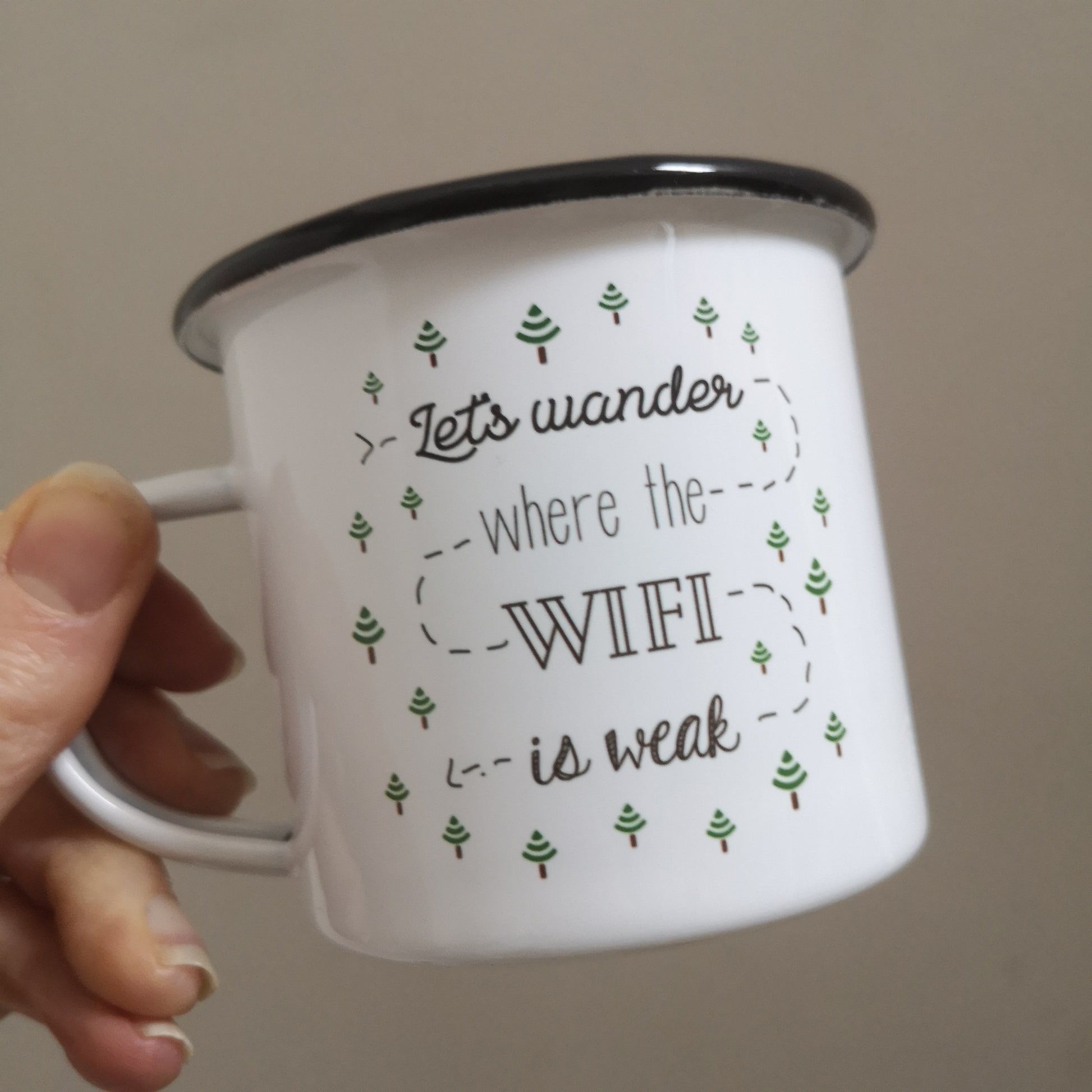 Another angle of a White enamel mug with a black rim with the following on the front - 'Let's wander where the WIFI is weak' and lots of little trees that are upside down wifi signals