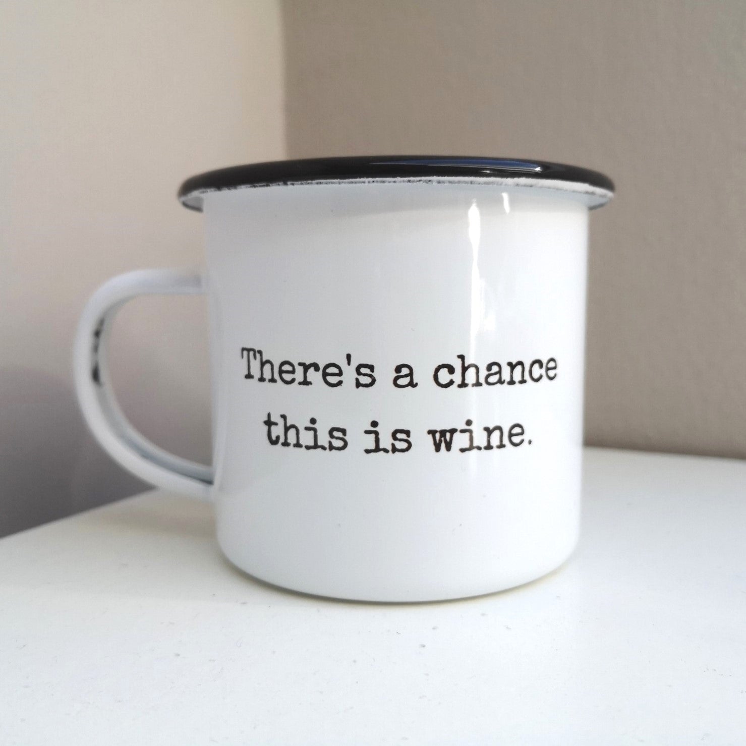 A White enamel mug with a black rim with the following on the front in black and white lettering - there's a chance this is wine