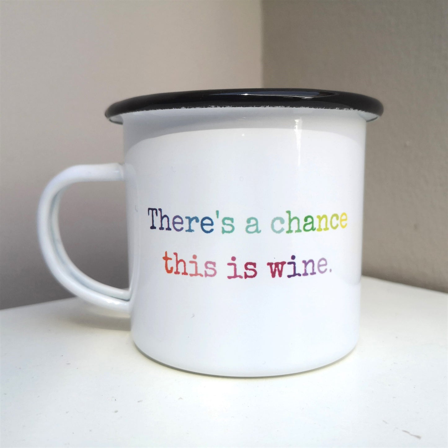 A  White enamel mug with a black rim with the following on the front in rainbow lettering - there's a chance this is wine